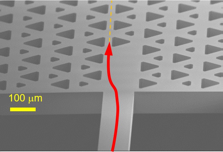 Détail d’une puce topologique en silicium pour la transmission d’émission THz. Le signal est injecté dans la puce par le pont situé en bas de l’image. La propagation topologique a lieu dans la puce sur le guide formé par les gros triangle situés face-à-face © IEMN, 2022.